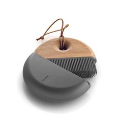 a wooden comb sitting on top of a gray and black hair dryer next to it's holder