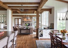 a large open concept kitchen and living room with wood flooring, white walls and beams