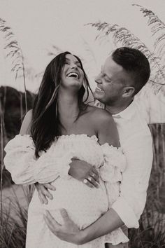 black and white photograph of a couple embracing each other in front of some tall grass