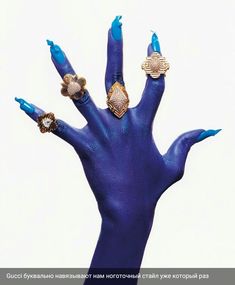 a woman's hand with blue painted nails and rings on her fingers, against a white background