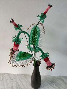 a vase filled with green plants on top of a white tablecloth covered floor next to a wall