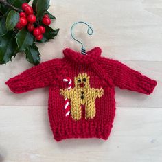 a red knitted sweater with a dog on it and candy canes next to it