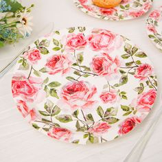 two plates with pink roses on them sitting on a table