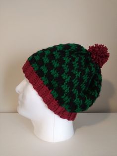 a green and black hat on top of a white mannequin head