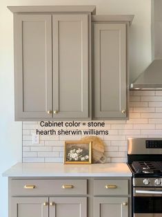 a kitchen with gray cabinets and white subway backsplash