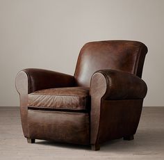 a brown leather recliner chair sitting on top of a hard wood floor next to a white wall