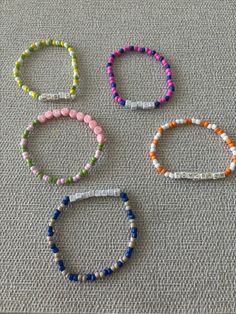 four different colored bracelets sitting on top of a cloth covered floor next to each other