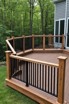 a wooden deck with black railings in front of a house