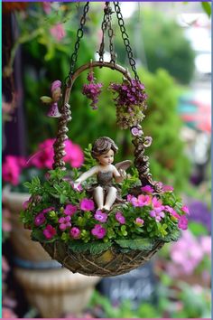 a fairy figurine sitting on top of a hanging basket filled with flowers