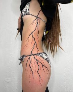 a woman is showing off her back with tree branches tattoo on it's side