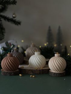 three ornaments sitting on top of a table next to a christmas tree