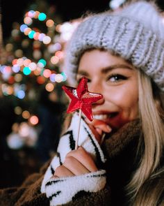 a woman holding a star shaped lollipop in front of a christmas tree