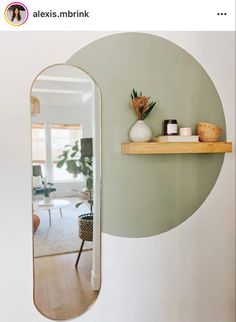 an oval mirror hanging on the wall next to a shelf