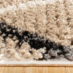 an area rug with black, white and grey colors on the floor in front of a wooden table