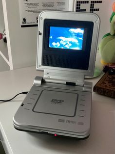 an old laptop computer sitting on top of a white desk next to a stuffed animal