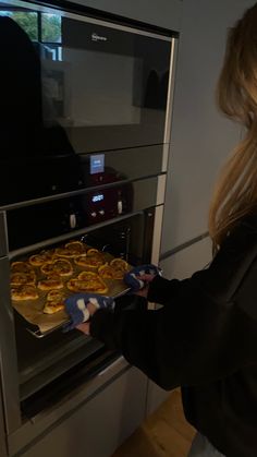 a woman is taking food out of the oven