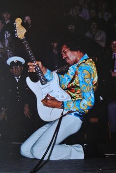 a man playing an electric guitar in front of a crowd