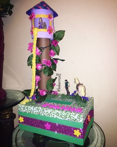 a cake that is decorated with flowers and decorations on top of a glass table in front of a wall