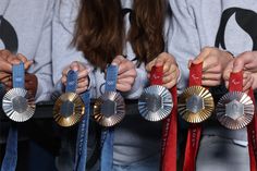 three women holding up their medals in front of them, with one woman's hands on the other