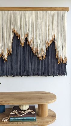 a wooden table topped with a book next to a wall hanging