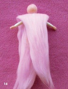 a small doll is laying on a pink blanket