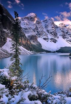 snow covered mountains surrounding a lake surrounded by trees