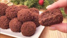 a person holding a chocolate cookie in front of some other cookies on a white plate