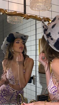 a woman is brushing her teeth in front of a mirror while wearing a cow print bathing suit