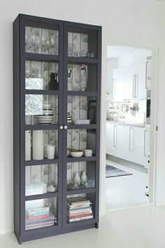 a purple bookcase with glass doors in a white and gray kitchen area next to a doorway