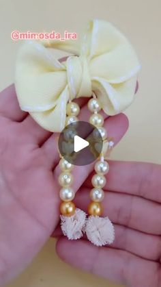 a hand holding a white bow with pearls and a pearl beaded necklace on it