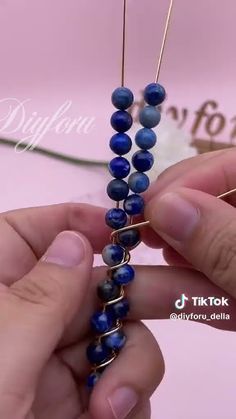 someone is making a bead necklace with blue beads