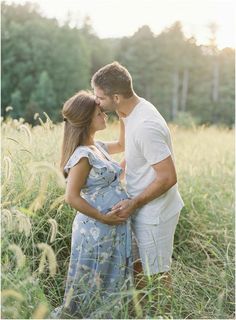 a man and woman are standing in tall grass with their hands on each other's shoulders