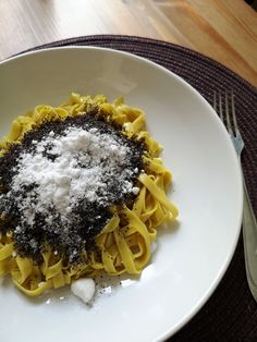 a white plate topped with pasta covered in powdered sugar