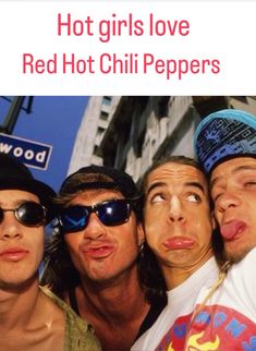 three men are posing for the camera in front of a red hot chili pepper sign