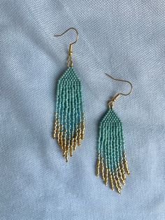 two pairs of beaded earrings sitting on top of a blue cloth