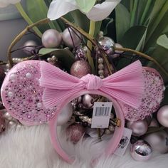 a pink bow headband with beads and pearls on it sitting next to some tulips