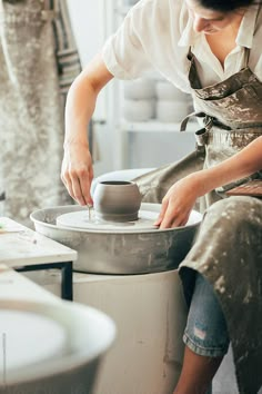 a woman in an apron is making a pot on a potter's wheel by jovan for stocks