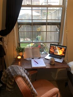 a laptop computer sitting on top of a wooden desk in front of a large window