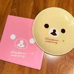 a plate with a bear face on it next to a pink notebook