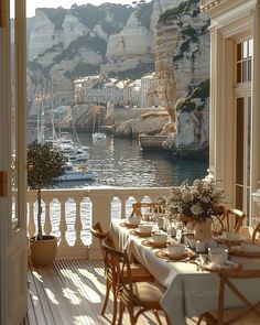 an outdoor dining area with tables and chairs overlooking the water in front of a cliff