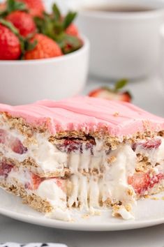 a piece of cake sitting on top of a white plate next to a bowl of strawberries