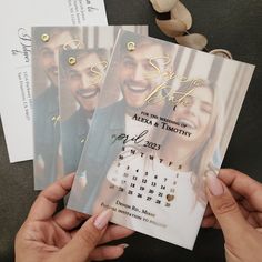 two people holding up some wedding save the dates cards with gold lettering on them,