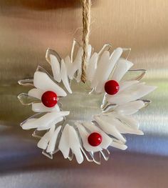 a christmas ornament hanging from a rope on top of a metal surface with red and white decorations