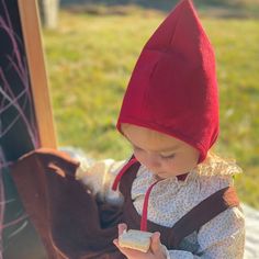 a small child wearing a red hat and holding a piece of food