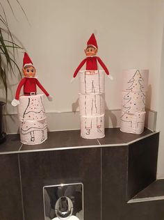 three elfs made out of toilet paper sitting on top of a counter