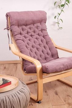 a purple chair sitting on top of a hard wood floor next to a potted plant