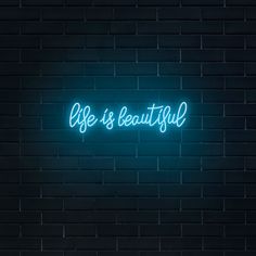 a neon sign that says life is beautiful on a brick wall in front of it