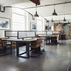 an industrial style dining room with tables and chairs, hanging lights and pictures on the wall