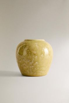 a yellow vase sitting on top of a white table