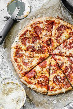 a sliced pizza sitting on top of a pan next to a knife and spatula